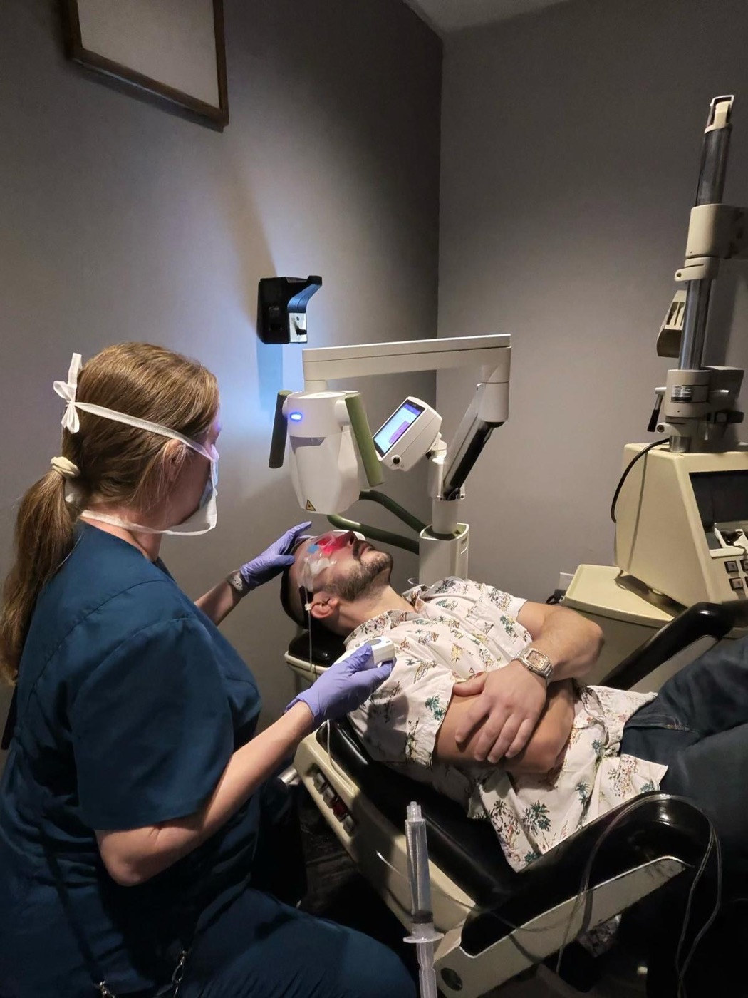A nurse steadying a patient and talking him through the procedure as the laser is positioned.