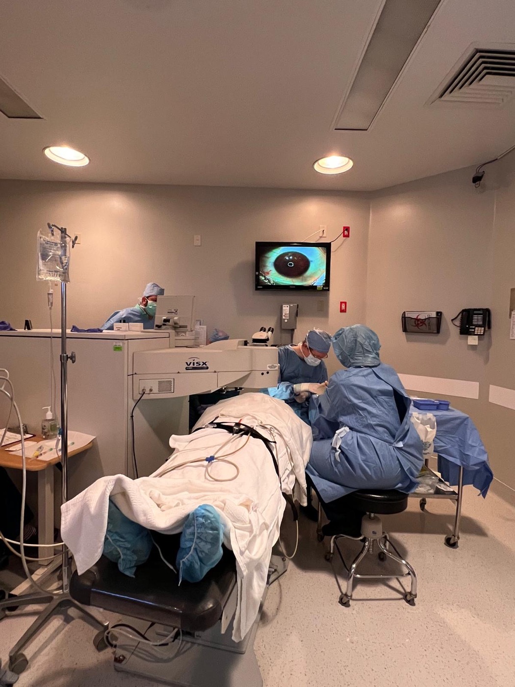 The laser suite from the doorway, the team positioned around the patient and the VISX system.